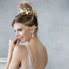 Braut mit einem eleganten, tiefen Dutt, geschmückt mit zarten Blumen, bereit für ihre Hochzeit.