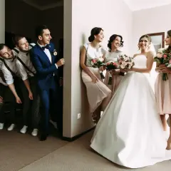 Bräutigam und Trauzeugen stehen Spalier, während die Brautjungfern mit Blumensträußen auf die Braut warten. Eine lustige Szene, die die **Trauzeugen Pflicht** humorvoll darstellt.