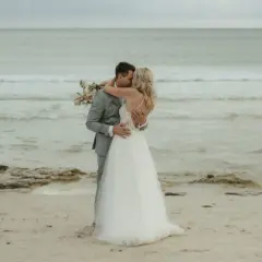 Ein Brautpaar küsst sich am Strand. Sie heiraten auf Mallorca am Strand, umgeben vom Meer und Sand.