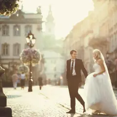 Ein frisch vermähltes Paar genießt den Moment nach der standesamtlichen Trauung, Hand in Hand auf einer sonnigen Straße.