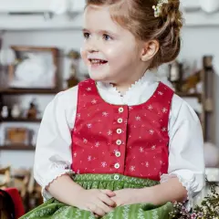 Ein fröhliches Mädchen im Dirndl mit einer hübschen Schleife im Haar. Die Tracht ist für Kinder perfekt.