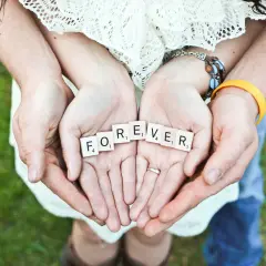Hände halten Scrabble-Steine mit "FOREVER". Ein Paar feiert seinen 42. Hochzeitstag.