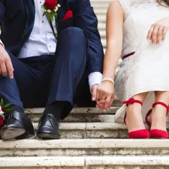 Brautpaar hält Händchen, rote Rosen & Schuhe. Perfekt für Ideen kleine standesamtliche hochzeit.
