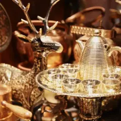 Glänzende bronzene Teekanne mit Tassen und Hirschfigur, perfekt für eine bronzene Hochzeit.