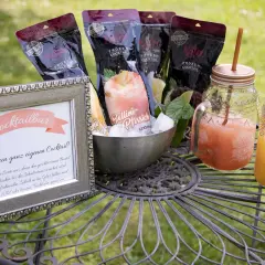 Cocktailbar-Schild und gefrorene Cocktails für eine Hochzeit. Mehrere Beutel mit gefrorenen Cocktails und zwei fertige Getränke in Gläsern mit Strohhalmen.