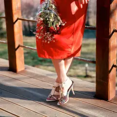 Frau in einem roten Kleid mit einem Blumenstrauß, bereit für eine Hochzeit.