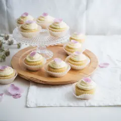 Zarte Cupcakes mit cremiger Glasur und rosa Blütenblättern – süße Ideen für eine Hochzeit.