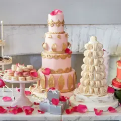 Ein prachtvolles Kuchenbuffet für eine Hochzeit: mehrstöckige Torten in Rosa und Rot, Macarons-Türme und Rosen.