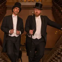 Zwei Herren im eleganten Frack mit Zylinder und Gehstock, ein perfektes Beispiel für den Dresscode Herren für einen besonderen Anlass.
