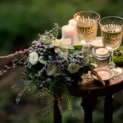 Romantische Szene mit Blumenstrauß, zwei Gläsern Sekt und Kerzenlicht. Ein Ring auf Moos deutet auf einen besonderen Anlass hin, vielleicht den 31. Hochzeitstag.