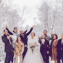 Brautpaar und Gäste werfen im Winter Schnee. Eine standesamtliche Hochzeit im Schnee mit fröhlichen Gästen.
