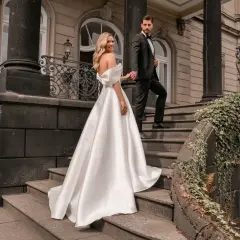Brautpaar auf Treppe, sie trägt ein elegantes weißes schleppe brautkleid, er im schwarzen Anzug.