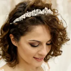 Brautfrisur kurze Haare Bob mit funkelndem Diadem. Lockige Haare umrahmen das Gesicht einer lächelnden Braut.