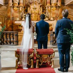 Trauzeugen stehen in der Kirche Spalier. Die Braut und der Bräutigam stehen vor dem Altar.
