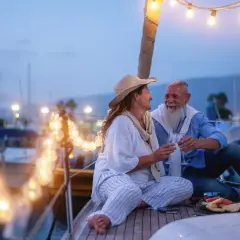 Ein glückliches Paar feiert seinen 44. Hochzeitstag auf einer Yacht. Die Bedeutung dieses Meilensteins wird durch ihre liebevolle Geste und die romantische Beleuchtung unterstrichen.