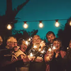 Familie feiert mit Wunderkerzen unter Lichterketten. Ein Lächeln, das die Bedeutung eines 75. Hochzeitstages widerspiegelt.