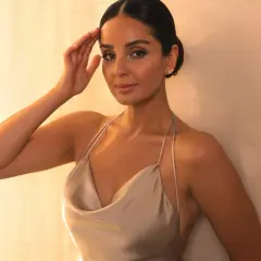 Eine Frau in einem eleganten, seidigen Kleid, das den **smart casual** Look perfektioniert. Ihre Hand ruht an ihrer Stirn, während sie in die Kamera blickt.