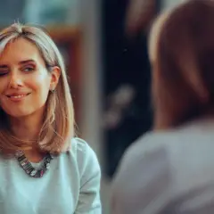 Frau mit einem schicken **long bob** zwinkert und lächelt in den Spiegel.