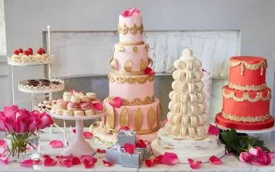 Ein prachtvolles Kuchenbuffet für eine Hochzeit: mehrstöckige Torten in Rosa und Rot, Macarons-Türme und Rosen.
