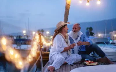 Ein glückliches Paar feiert seinen 44. Hochzeitstag auf einer Yacht. Die Bedeutung dieses Meilensteins wird durch ihre liebevolle Geste und die romantische Beleuchtung unterstrichen.