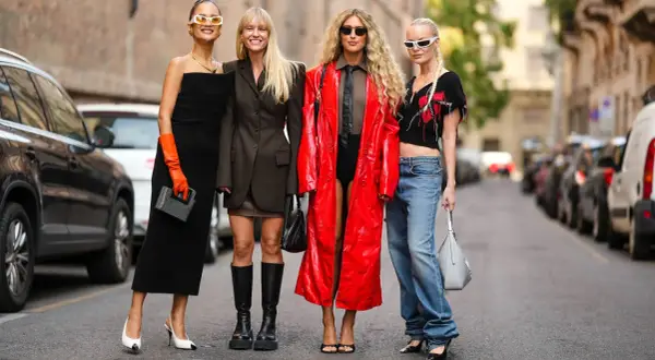 Vier Frauen präsentieren unterschiedliche **dresscodes Frauen**: von elegantem Schwarz über lässige Jeans bis hin zu auffälligem Rot.
