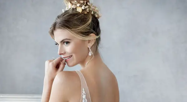 Braut mit einem eleganten, tiefen Dutt, geschmückt mit zarten Blumen, bereit für ihre Hochzeit.