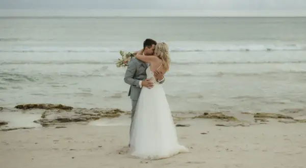 Ein Brautpaar küsst sich am Strand. Sie heiraten auf Mallorca am Strand, umgeben vom Meer und Sand.