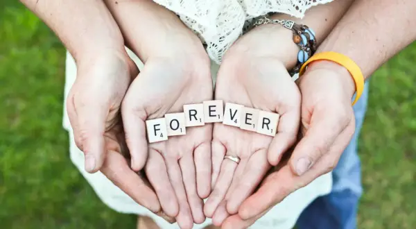 Hände halten Scrabble-Steine mit "FOREVER". Ein Paar feiert seinen 42. Hochzeitstag.