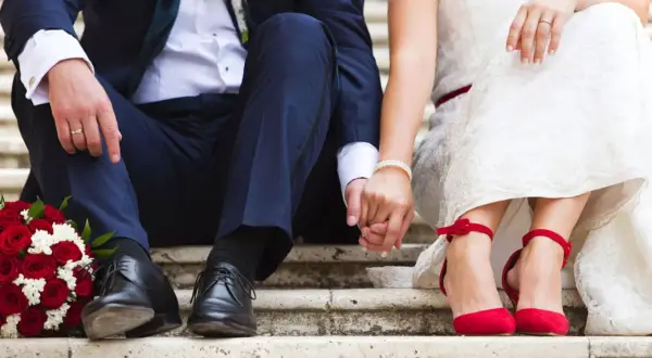 Brautpaar hält Händchen, rote Rosen & Schuhe. Perfekt für Ideen kleine standesamtliche hochzeit.