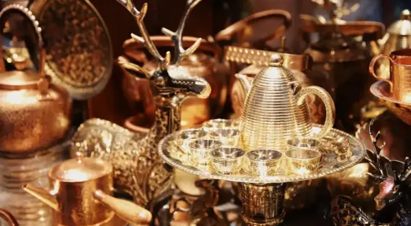 Glänzende bronzene Teekanne mit Tassen und Hirschfigur, perfekt für eine bronzene Hochzeit.