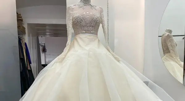 Ein prachtvolles, elfenbeinfarbenes Brautkleid mit einem hochgeschlossenen, bestickten Oberteil und einem voluminösen Tüllrock. Dieses Kleid könnte das Hochzeitskleid einer Kaiserin sein.