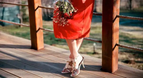 Frau in einem roten Kleid mit einem Blumenstrauß, bereit für eine Hochzeit.
