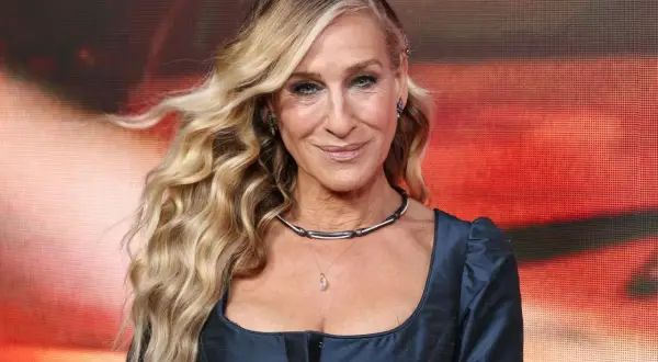 Sarah Jessica Parker mit ihrem charakteristischen beach waves bob, lächelnd in einem dunkelblauen Kleid.