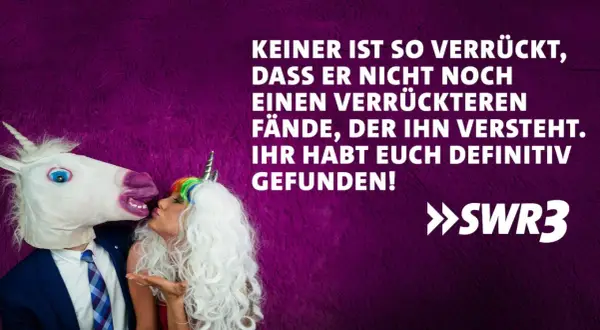 Ein Mann mit Einhornmaske küsst eine Frau mit Einhorn-Haarreif. Ein lustig-witziges Bild, das perfekt zum Hochzeitstag passt!