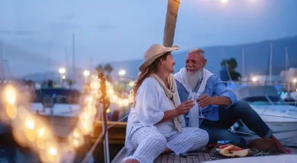 Ein glückliches Paar feiert seinen 44. Hochzeitstag auf einer Yacht. Die Bedeutung dieses Meilensteins wird durch ihre liebevolle Geste und die romantische Beleuchtung unterstrichen.