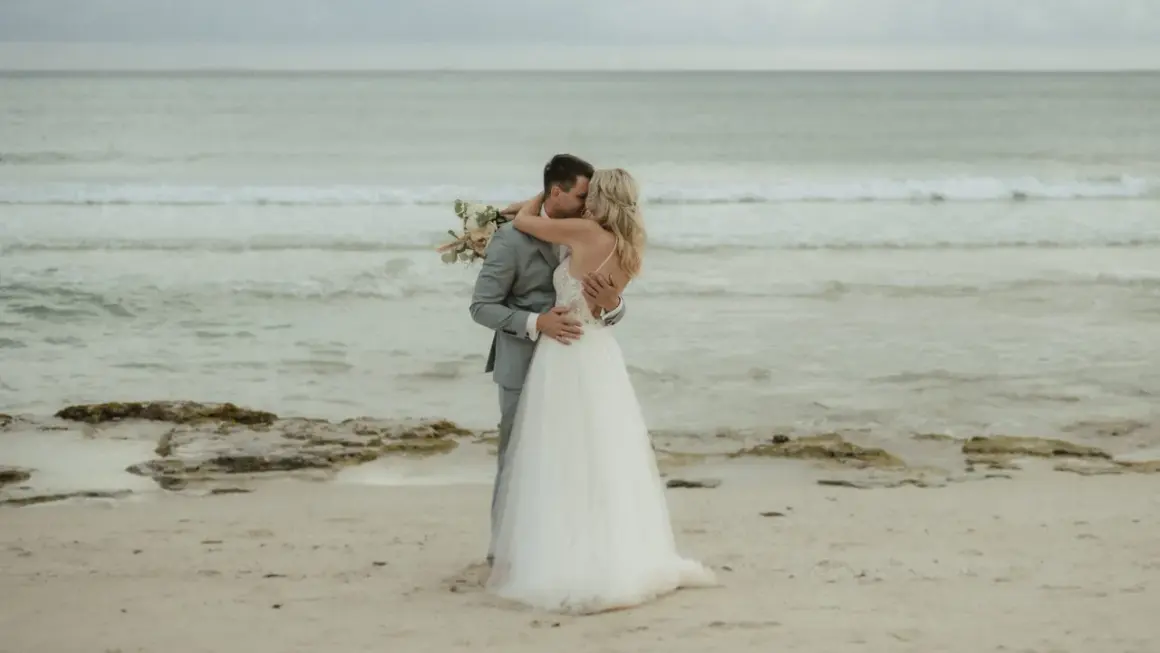 Ein Brautpaar küsst sich am Strand. Sie heiraten auf Mallorca am Strand, umgeben vom Meer und Sand.
