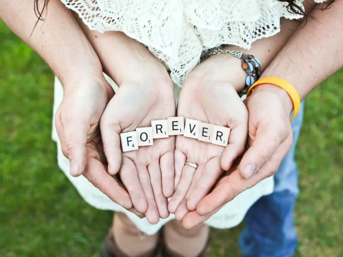 Hände halten Scrabble-Steine mit "FOREVER". Ein Paar feiert seinen 42. Hochzeitstag.