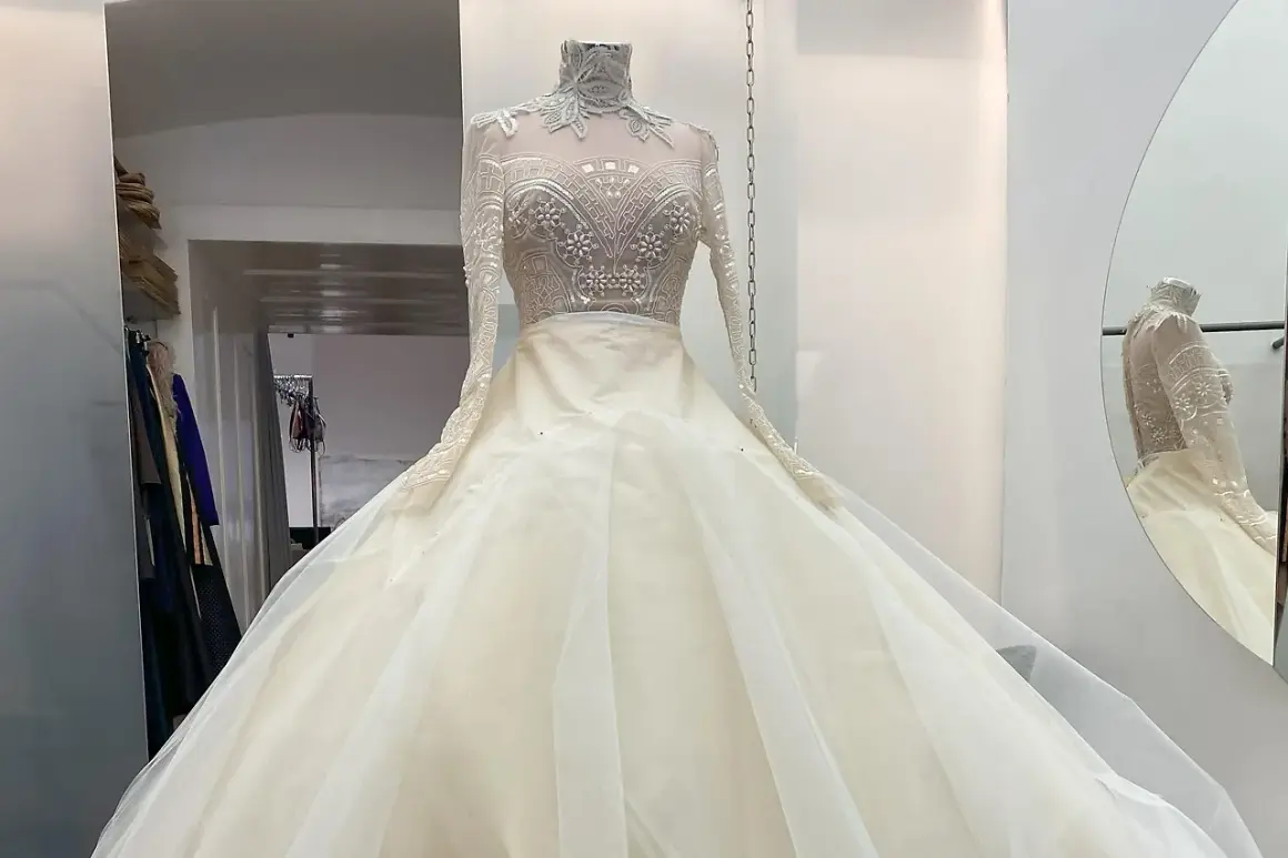Ein prachtvolles, elfenbeinfarbenes Brautkleid mit einem hochgeschlossenen, bestickten Oberteil und einem voluminösen Tüllrock. Dieses Kleid könnte das Hochzeitskleid einer Kaiserin sein.