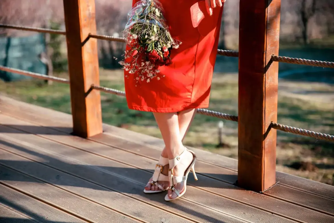 Frau in einem roten Kleid mit einem Blumenstrauß, bereit für eine Hochzeit.