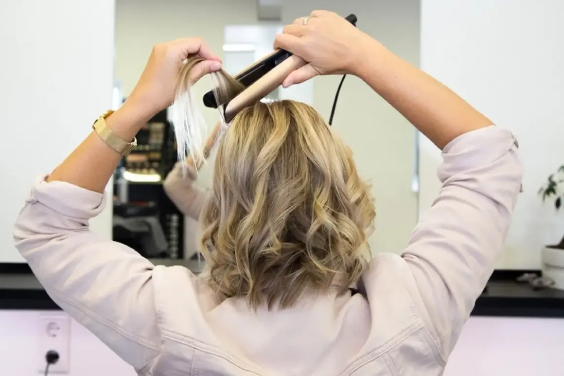Frau stylt ihre Haare mit einem Glätteisen, um sanfte Wellen zu kreieren.