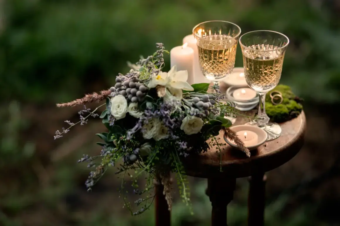 Romantische Szene mit Blumenstrauß, zwei Gläsern Sekt und Kerzenlicht. Ein Ring auf Moos deutet auf einen besonderen Anlass hin, vielleicht den 31. Hochzeitstag.