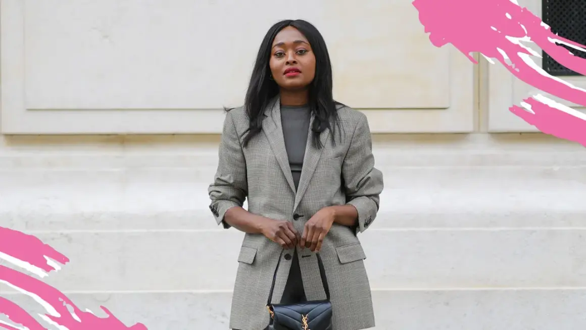 Frau in kariertem Blazer und dunklem Oberteil, perfekt für einen **business casual** Look, hält eine schwarze Handtasche.