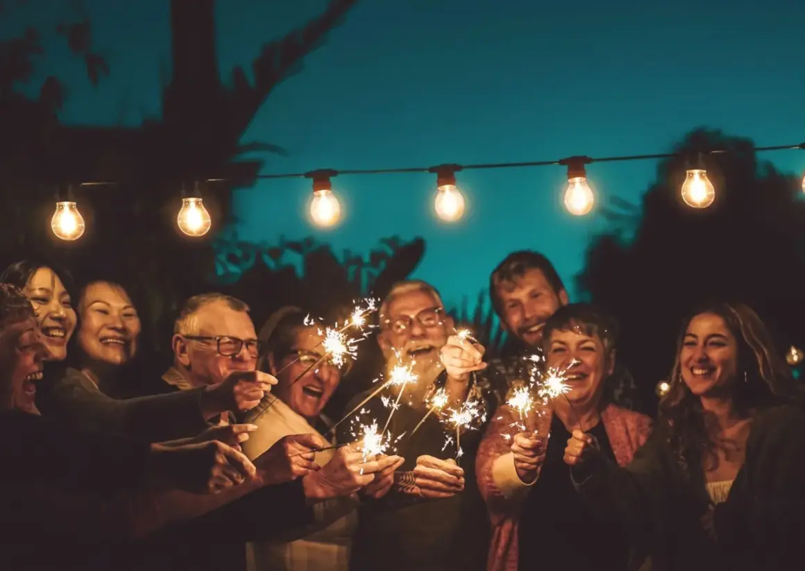 Familie feiert mit Wunderkerzen unter Lichterketten. Ein Lächeln, das die Bedeutung eines 75. Hochzeitstages widerspiegelt.