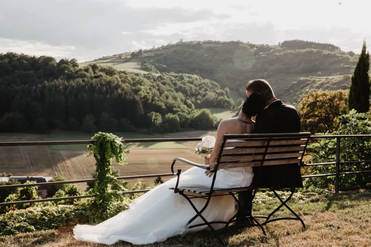Brautpaar genie&szlig;t den Ausblick auf einem Weingut. Die romantische weingut hochzeit wird durch die malerische Landschaft und das warme Abendlicht perfekt eingefangen.