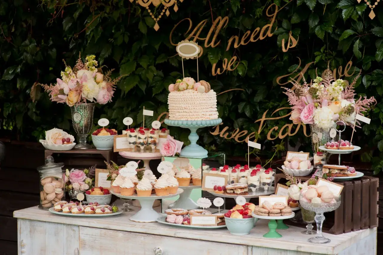 Ein üppiges Kuchenbuffet Hochzeit mit Macarons, Cupcakes, Torten und Blumen.