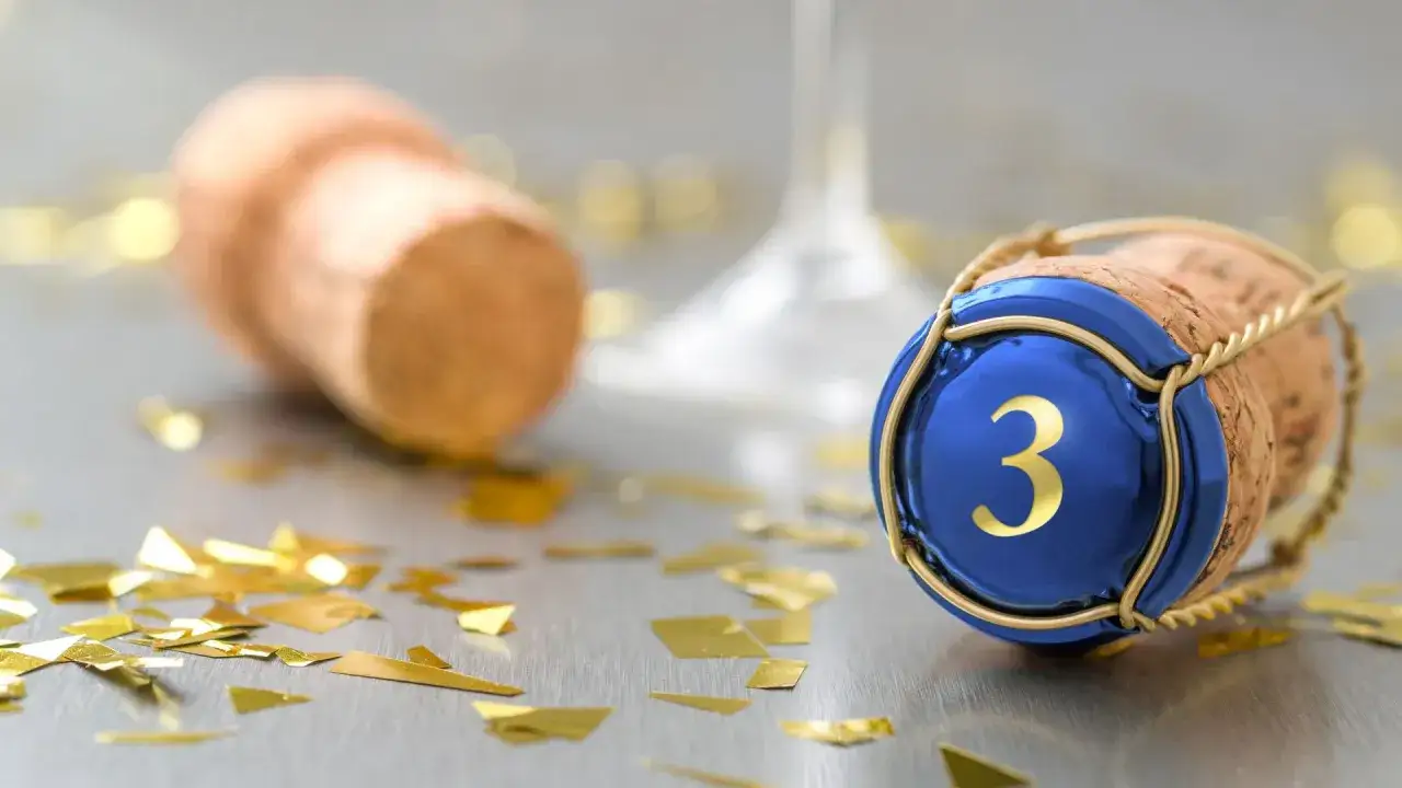 Sektkorken mit der Zahl 3, Konfetti und ein Weinglas. Ein Symbol für den 3 hochzeitstag bedeutung.