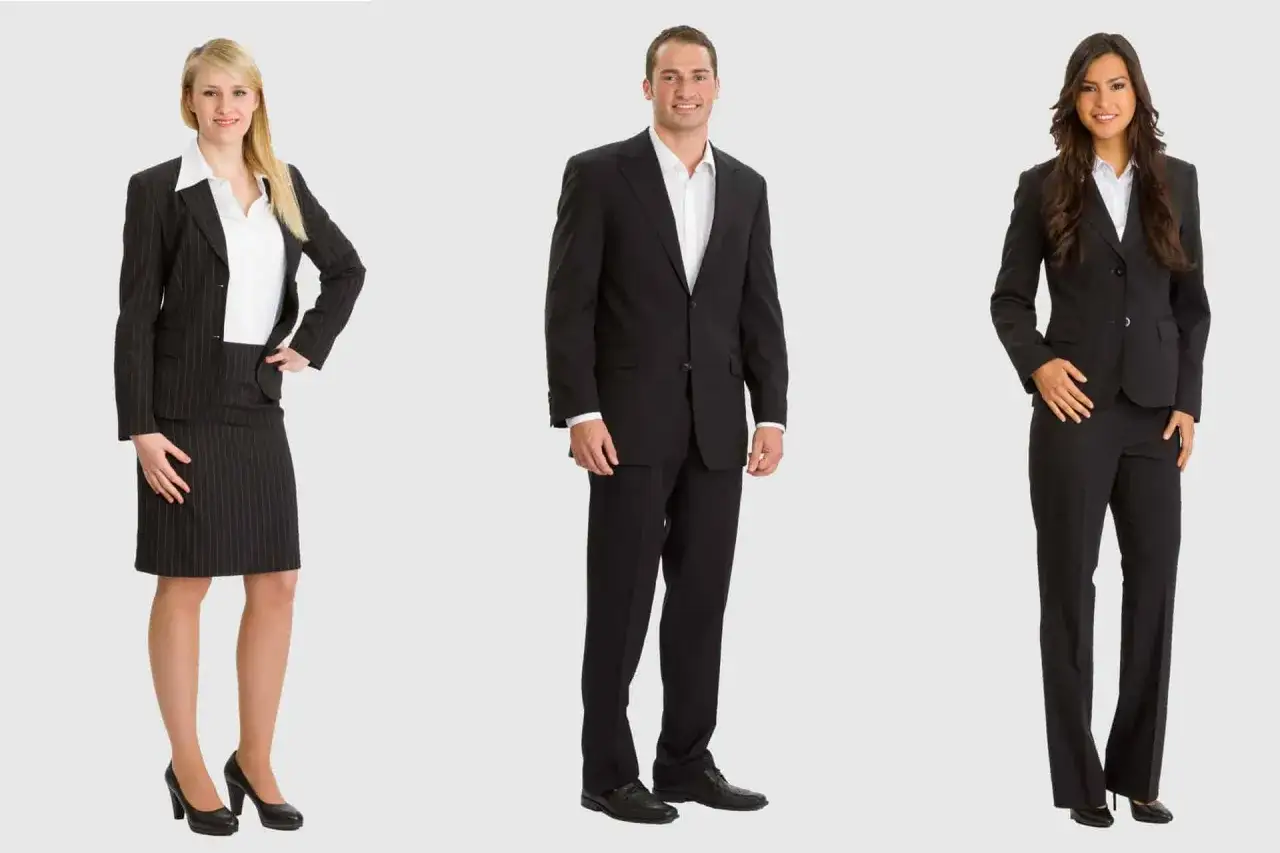 Drei Personen in eleganter business attire: eine Frau im Nadelstreifen-Kostüm, ein Mann im schwarzen Anzug und eine Frau in einem schwarzen Hosenanzug.