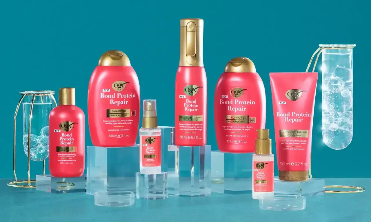 OGX Bond Protein Repair Produkte für strapaziertes Haar, darunter Shampoo, Conditioner und Maske, auf blauem Hintergrund.