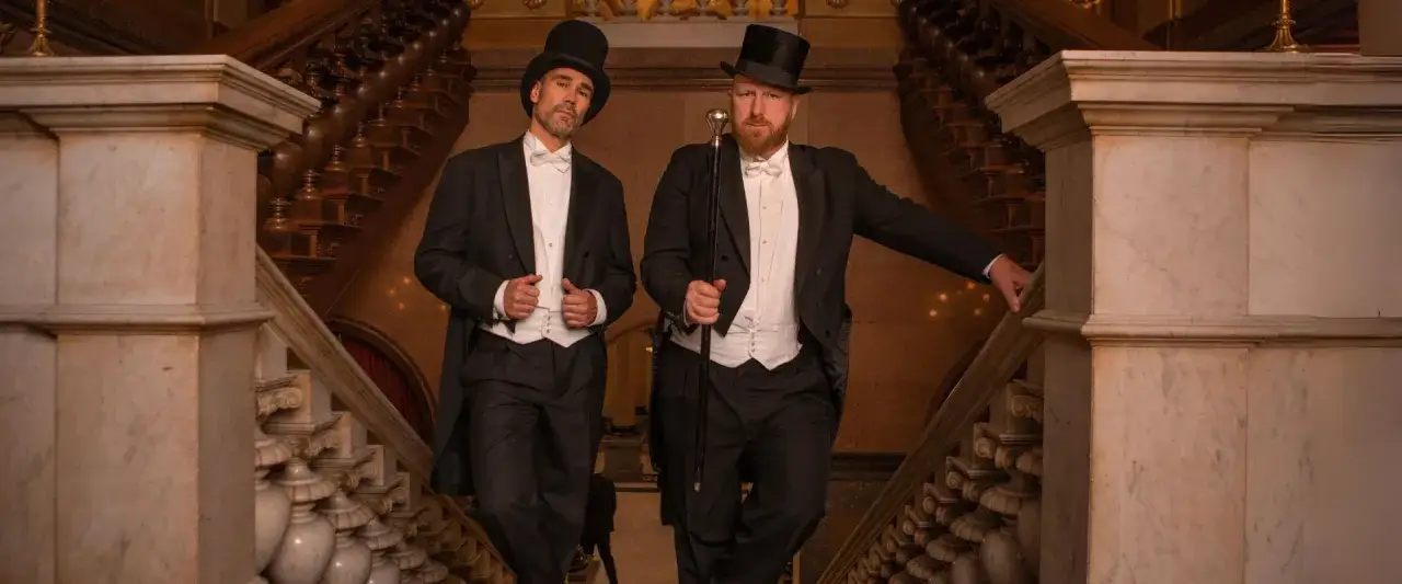 Zwei Herren im eleganten Frack mit Zylinder und Gehstock, ein perfektes Beispiel für den Dresscode Herren für einen besonderen Anlass.