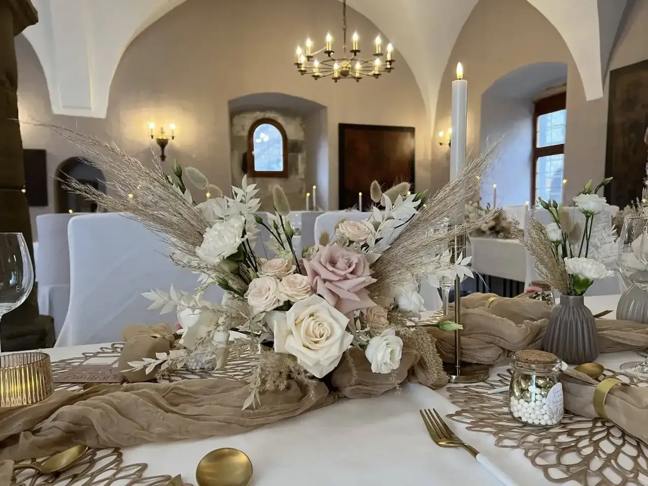 Festlich gedeckter Tisch mit Blumenarrangement, Kerzen und goldenen Akzenten. Ein Zeichen für den 14. Hochzeitstag Bedeutung.
